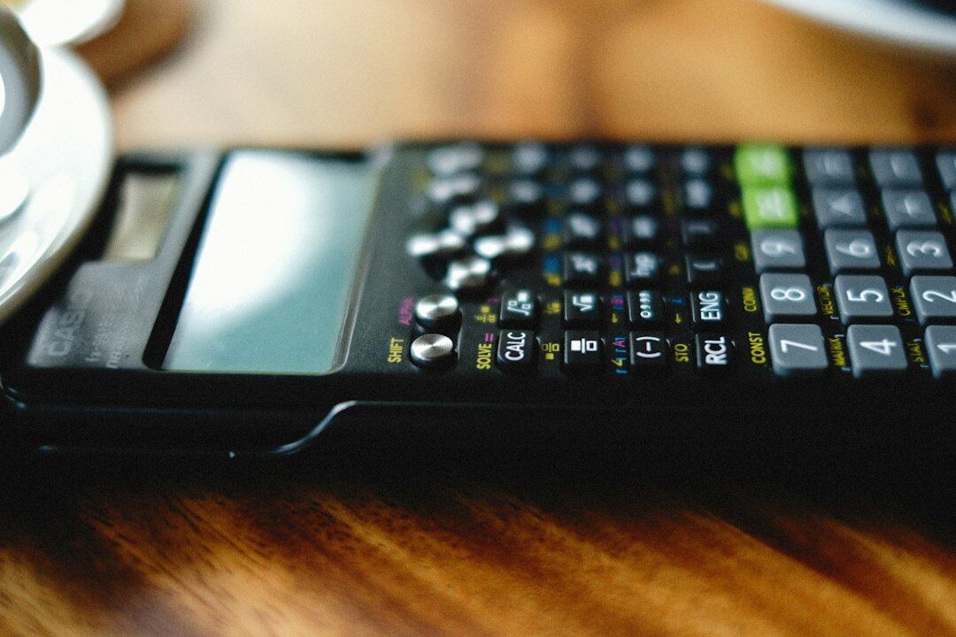 A researcher's desk with printed statistical tables, a calculator and a laptop showing regression charts